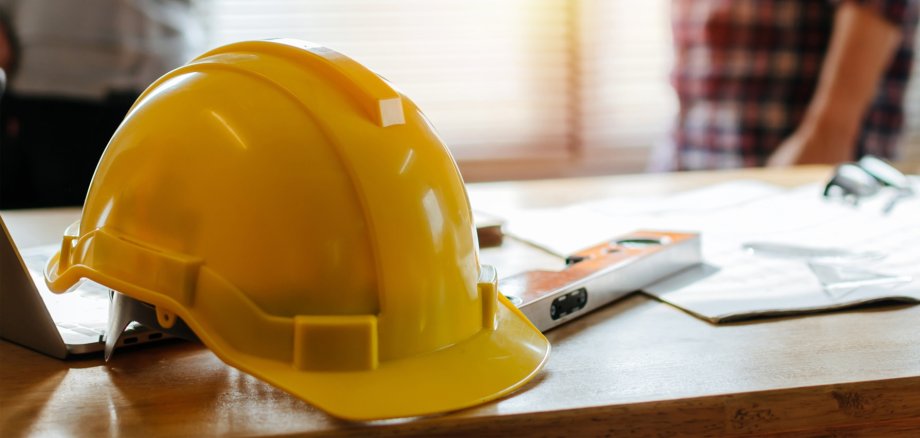 yellow safety helmet on workplace desk with construction worker